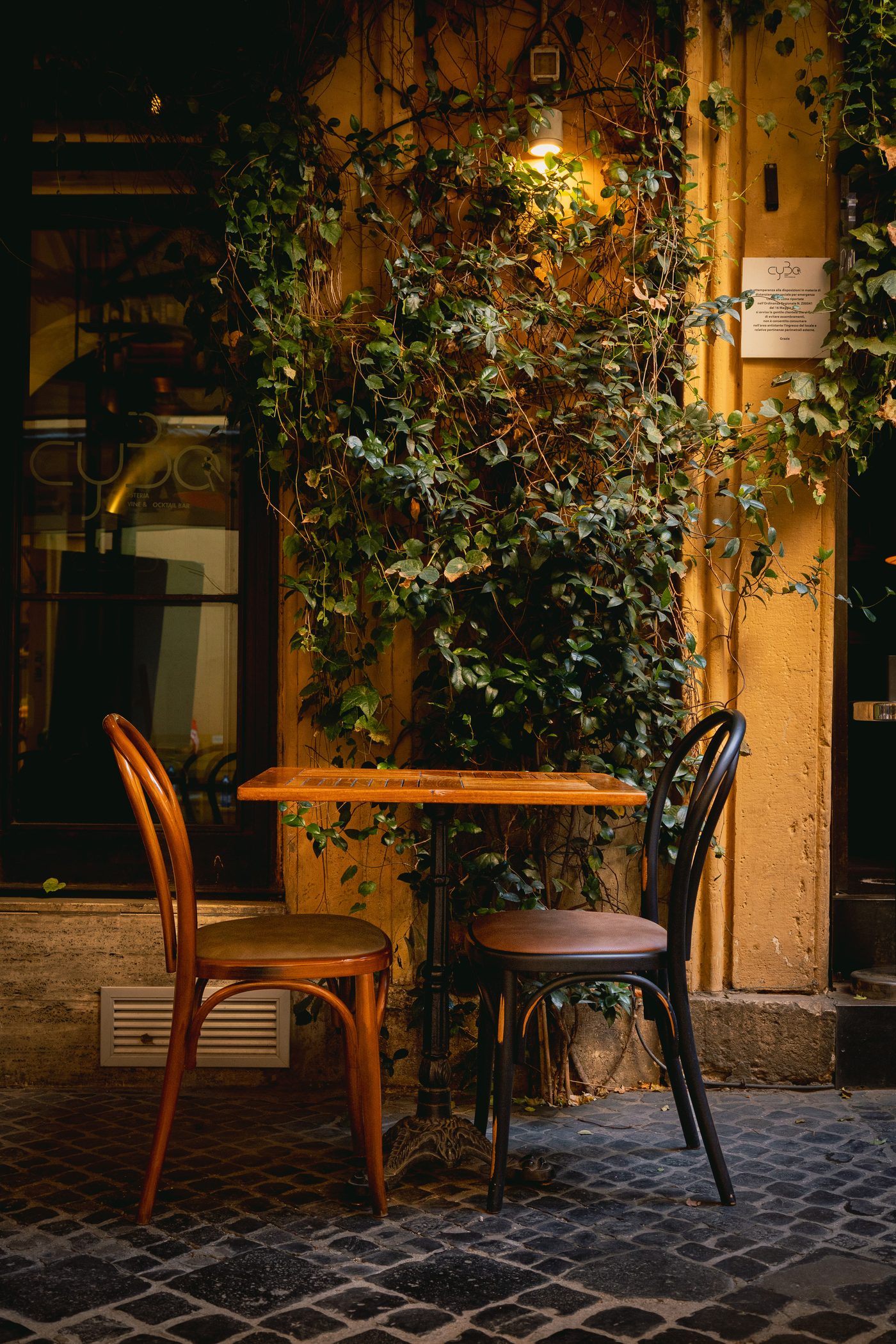 Esterno di un ristorante nel centro di Roma, tavolino con sedie davanti a una parete con edera