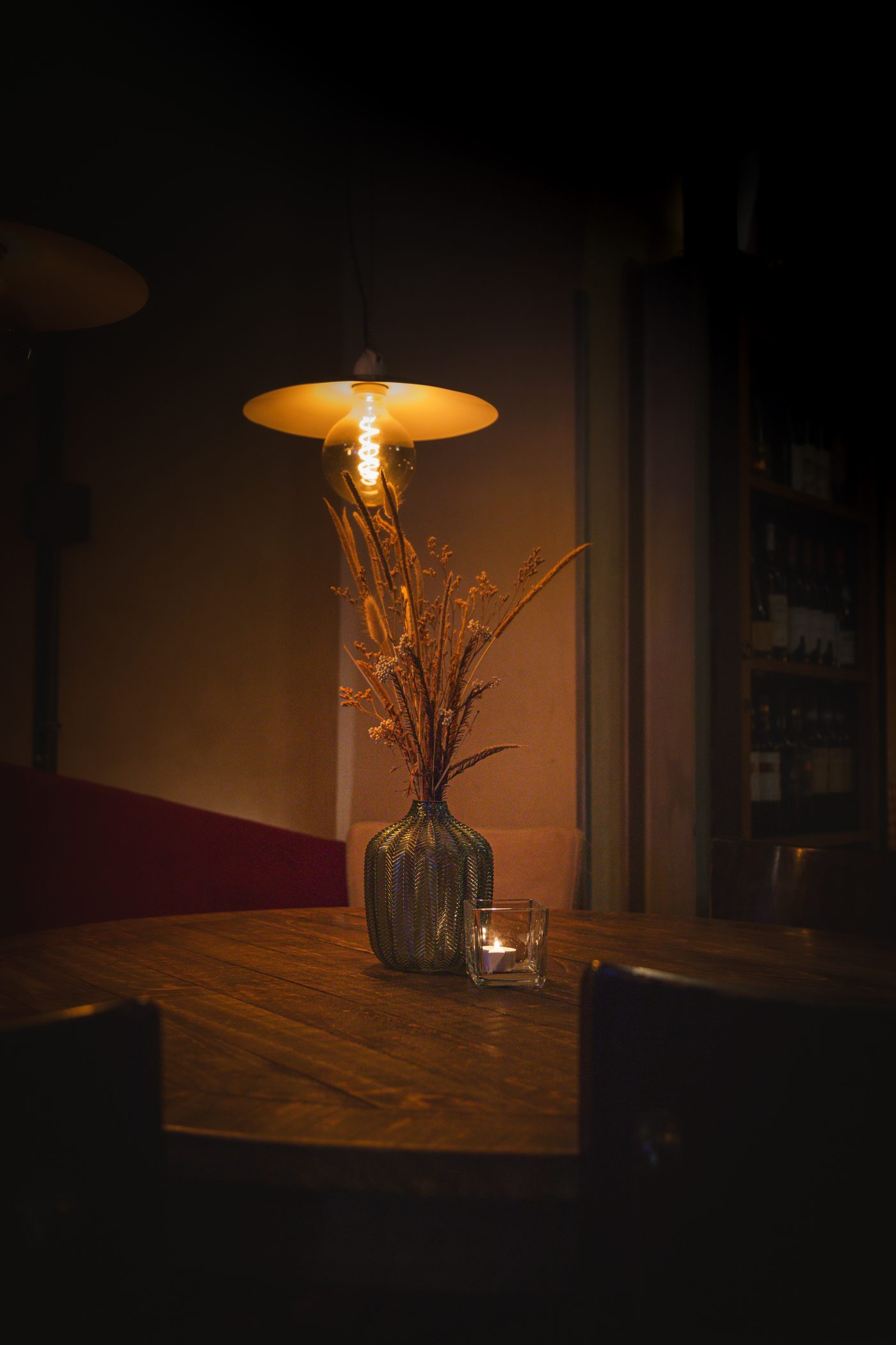 Sala di un ristorante la sera con lampada sospesa e tavolo apparecchiato