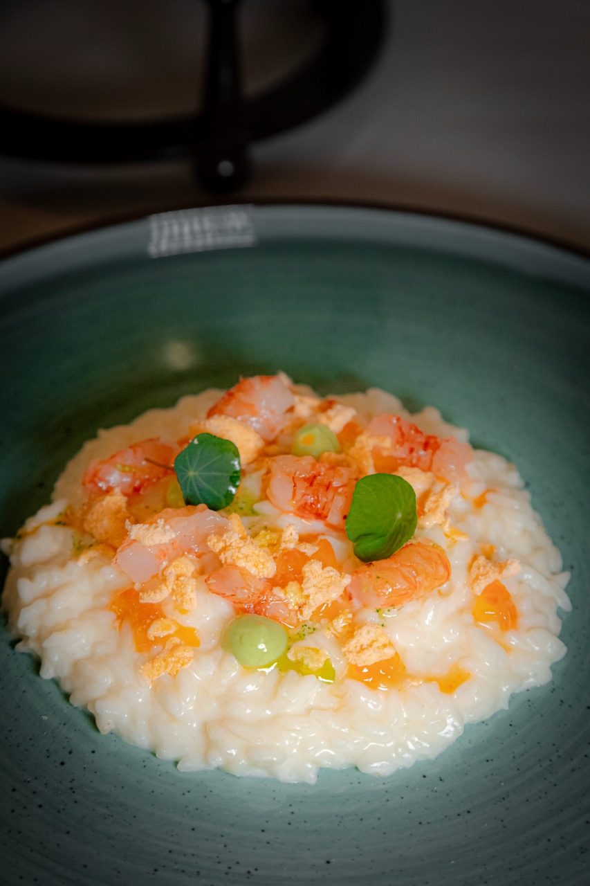 Risotto ai crostacei fotografato a 45 gradi su piatto in ceramica verde